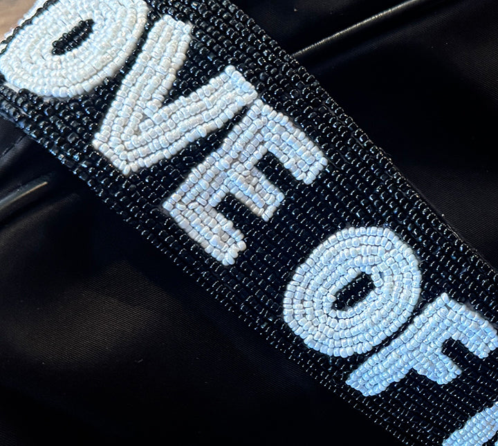 Close-up bead detail of "FOR THE LOVE OF RODEO" strap on a dark background