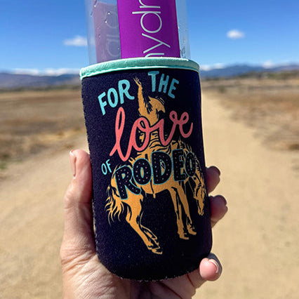 Hand holding a water bottle with a colorful sleeve against a mountain landscape